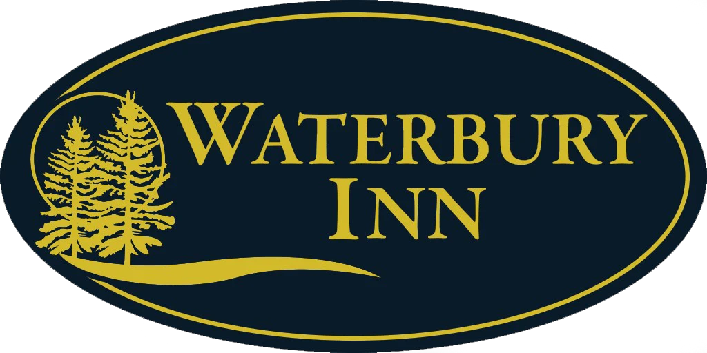 Waterbury Inn logo featuring two pine trees and flowing lines in gold, enclosed within a dark navy oval with gold trim.